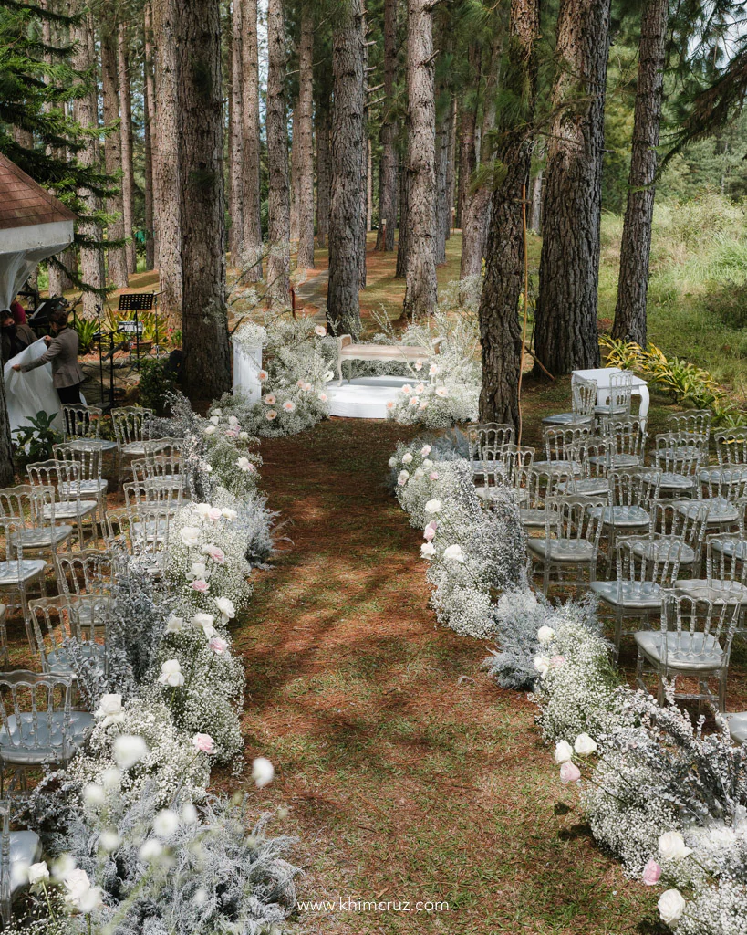 forest themed wedding ceremony twilight feels with pine trees as backdrop and white gypsophilas on aisle pathway by Khim Cruz at scenic Bukidnon