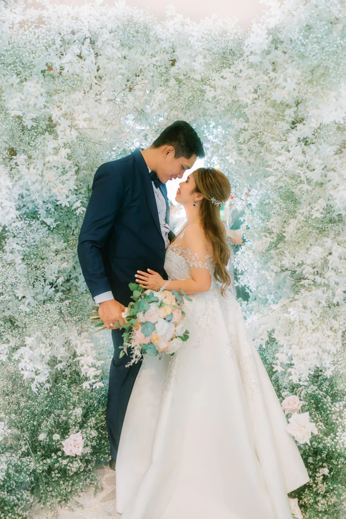 bride and groom against their entrance floral arch of their sophisticated elegant wedding ceremony