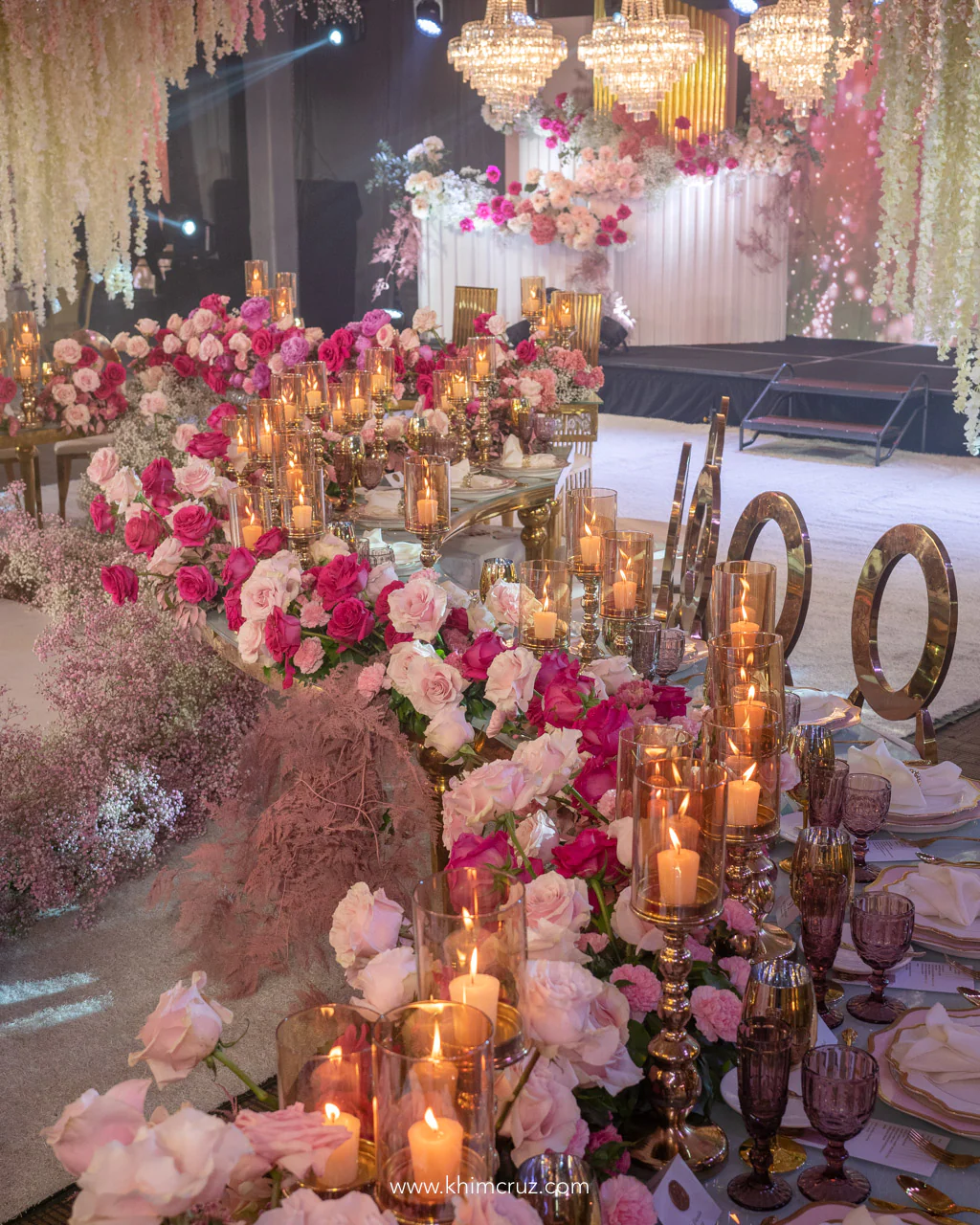 pink flowers table centerpieces with candles arranged on top of a curved table