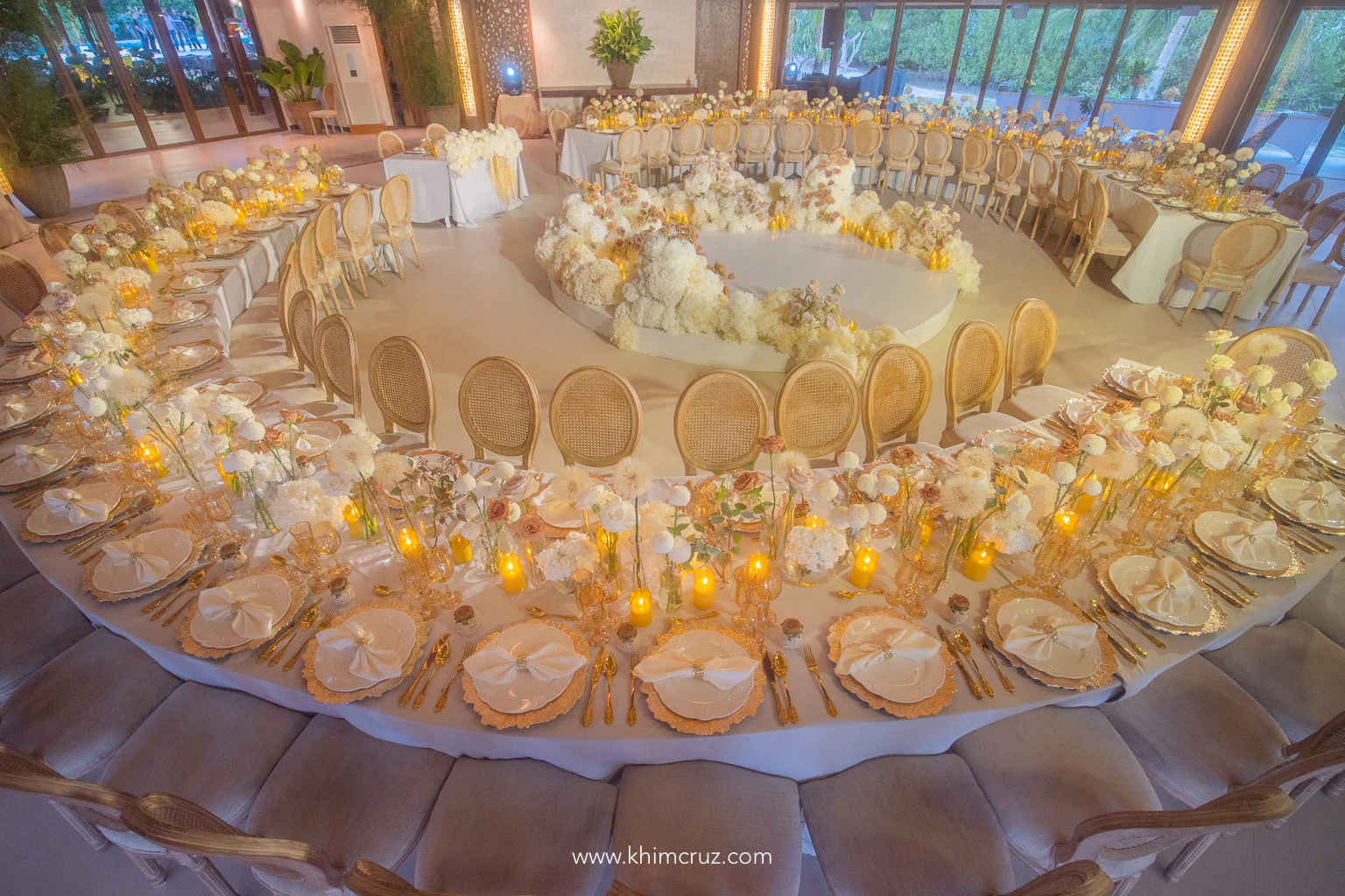warm glow of candles on circular wedding reception table with beautifully arranged flowers