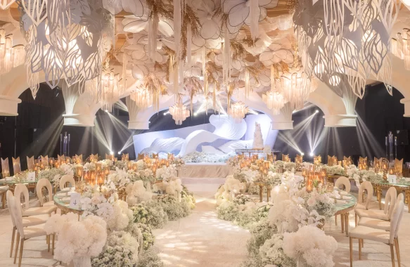 a wave-like backdrop sets the stage with suspended florals and arching ceiling structures add depth and elegance to this wedding reception