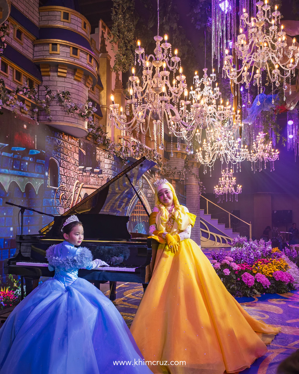 celebrants on a grand piano with chandeliers and princess castle on the background on this princess themed celebration