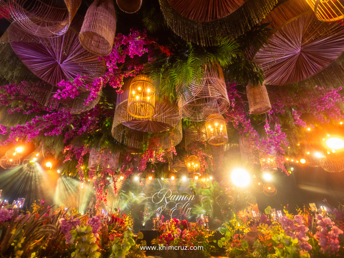 A wedding reception ceiling installation that glows with golden light and lush tropical sophistication
